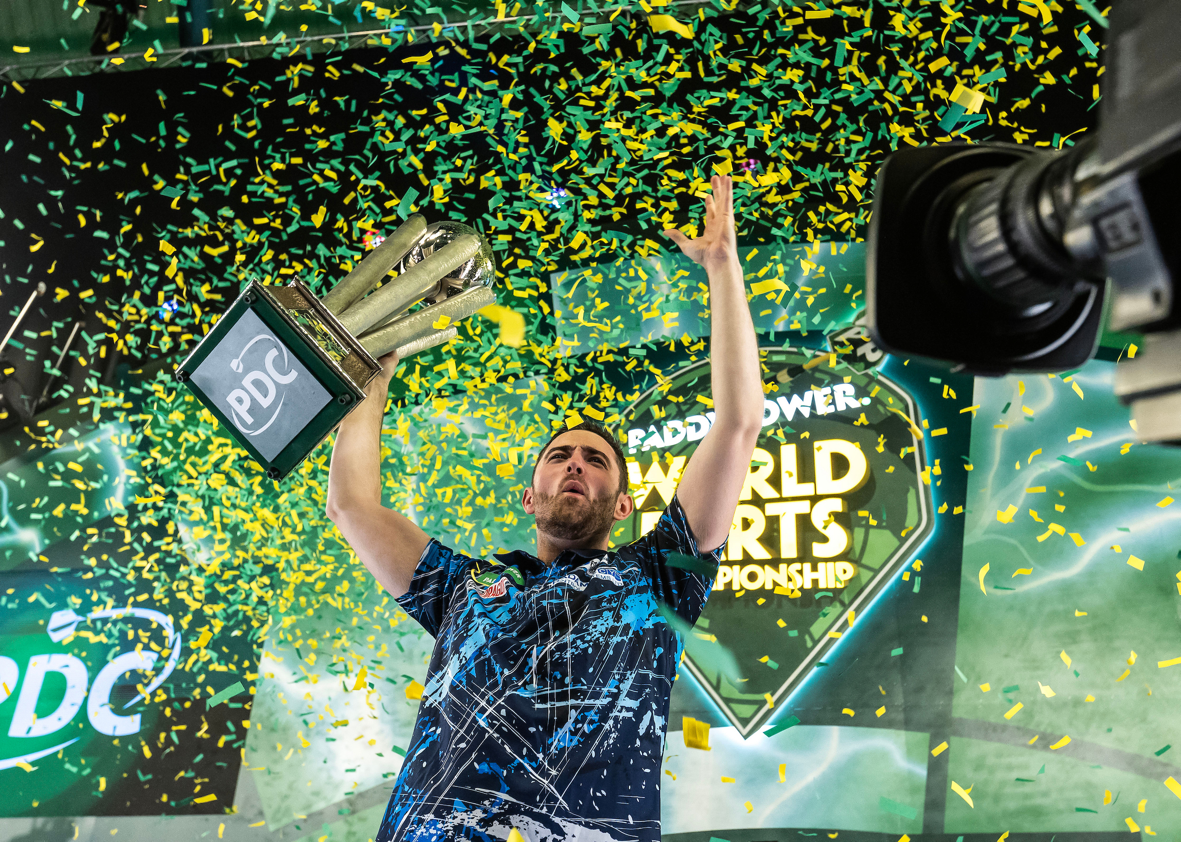 Der amtierende Weltmeister Luke Humphries mit seiner Trophäe.