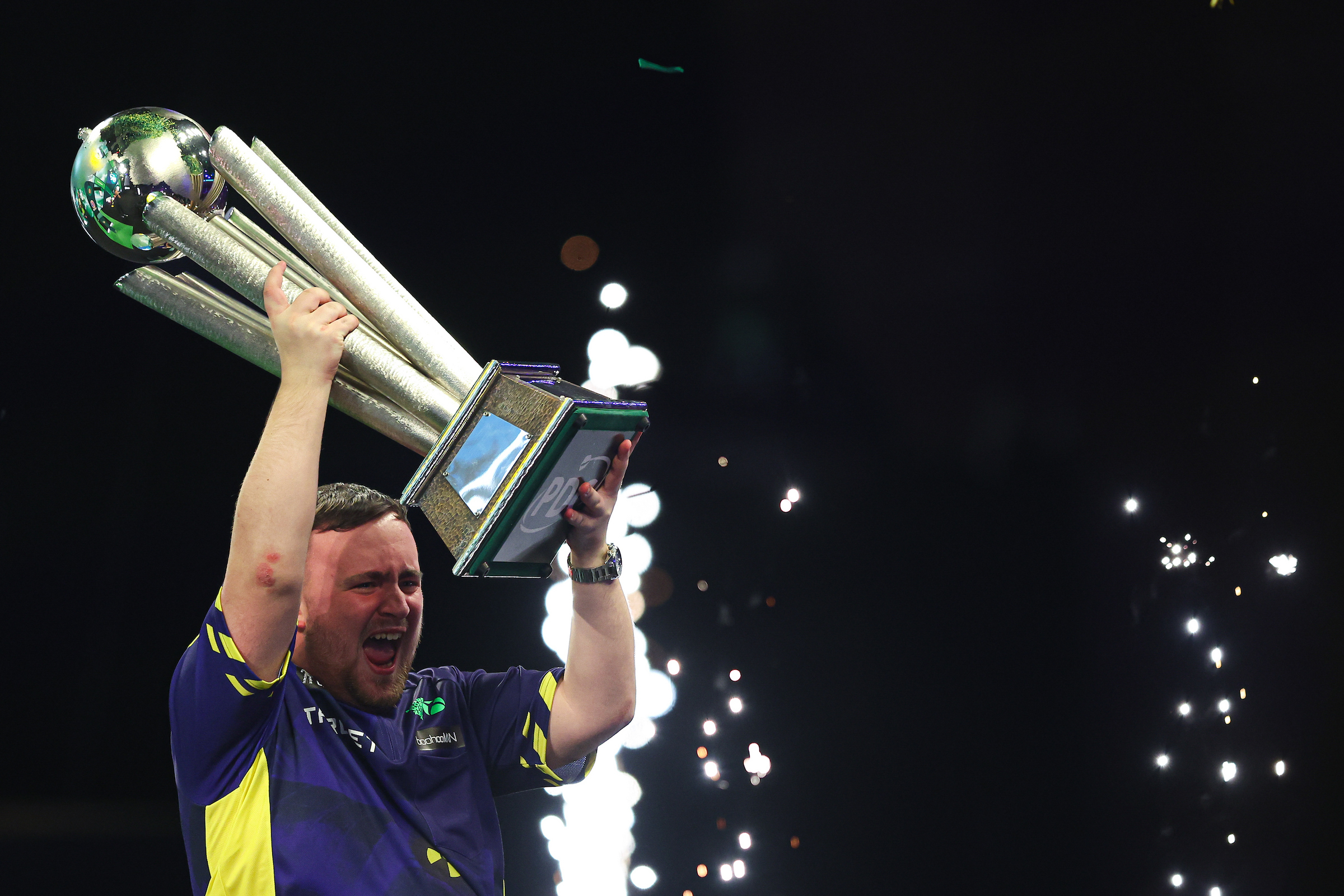 Luke Littler jubelt leidenschaftlich mit nach oben gestrecktem Pokal nach seinem Sieg zum Weltmeister 2025